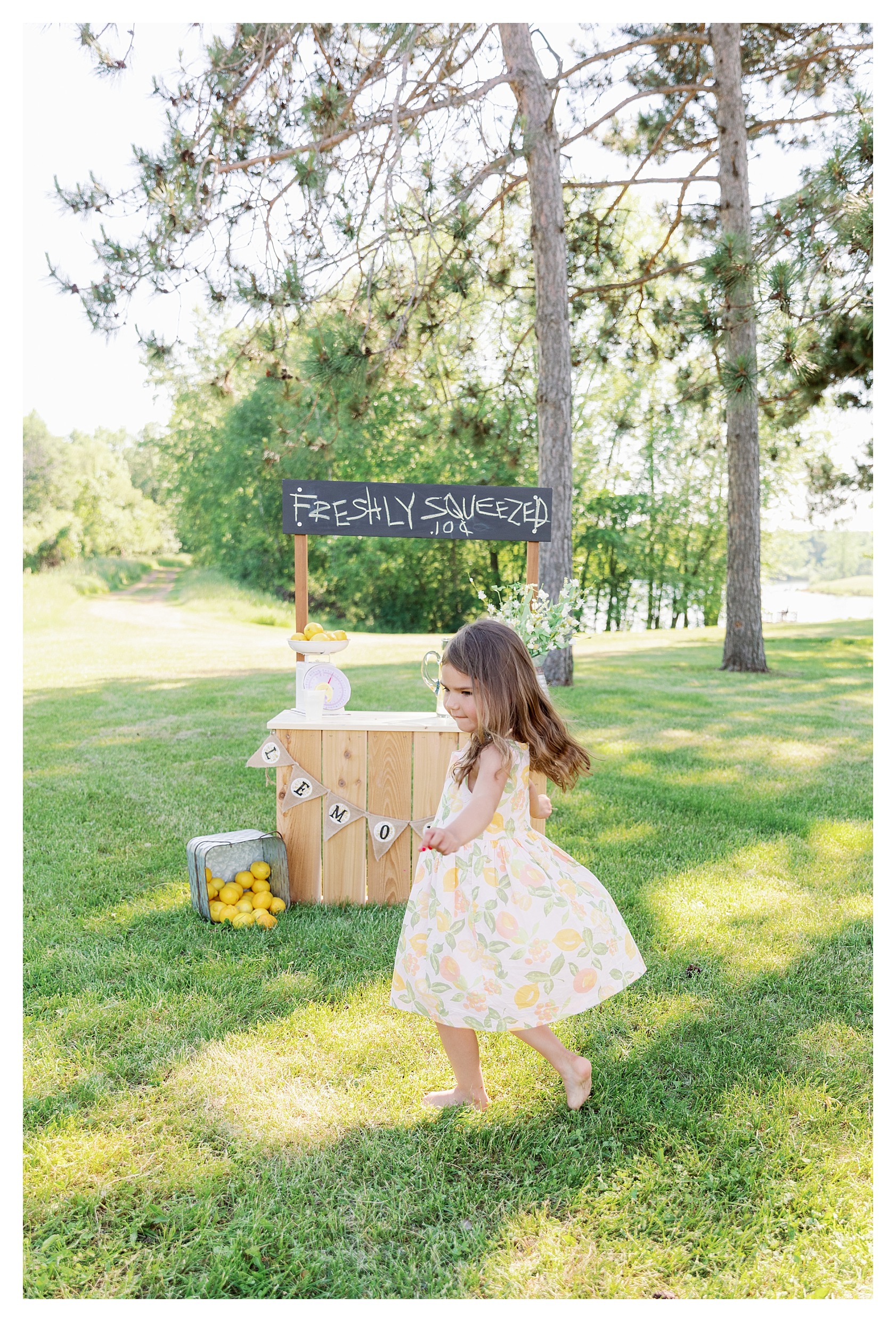 toddler girl twirls in her summer dress during her lemonade stand mini session in Wausau, WI at Sunnyvale Park
