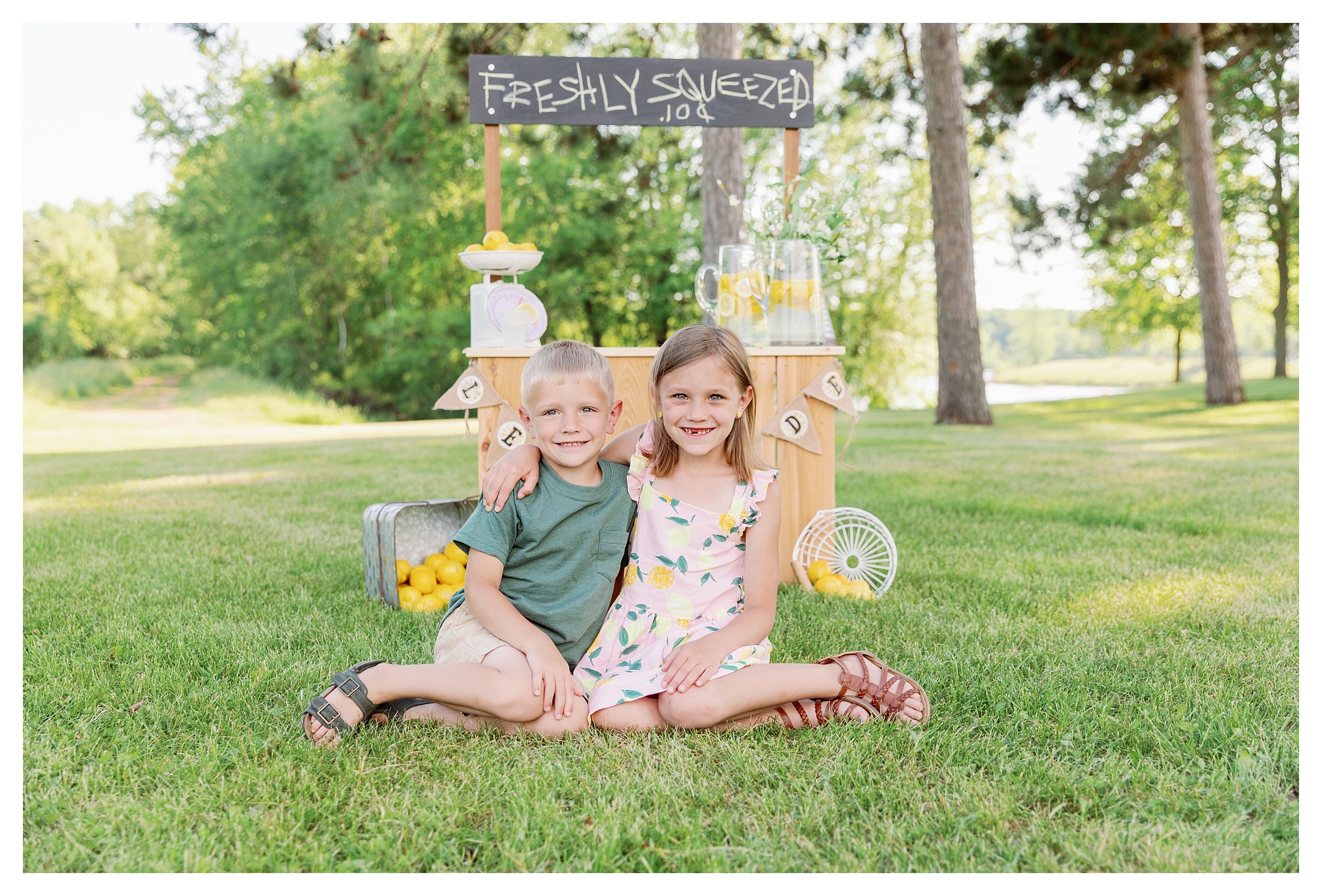 brother and sister pose in front of lemonade stand during their mini session at Sunnyvale Park