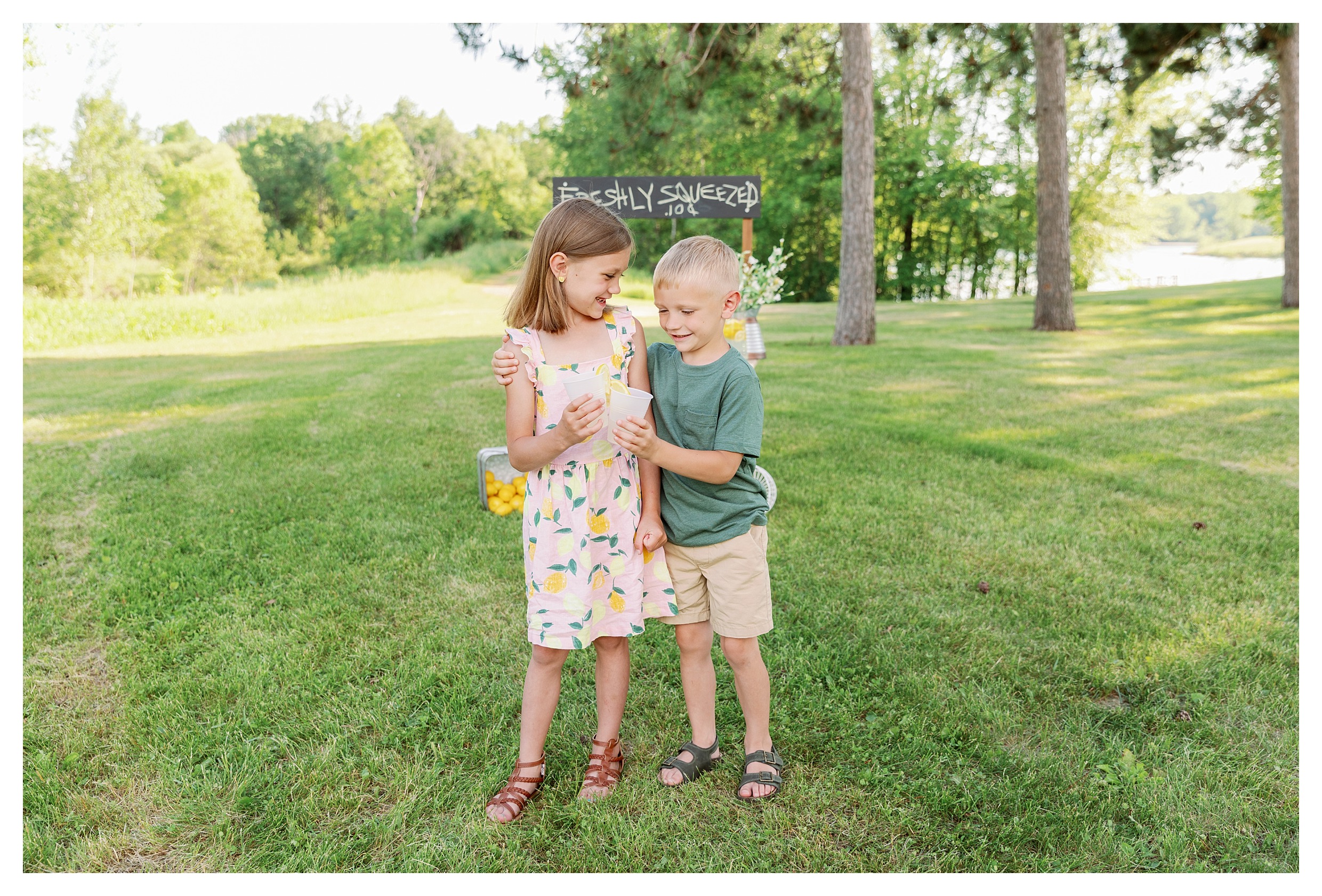 brother and sister pose during their lemonade stand mini session in Wausau, WI at Sunnyvale Park with their lemonade