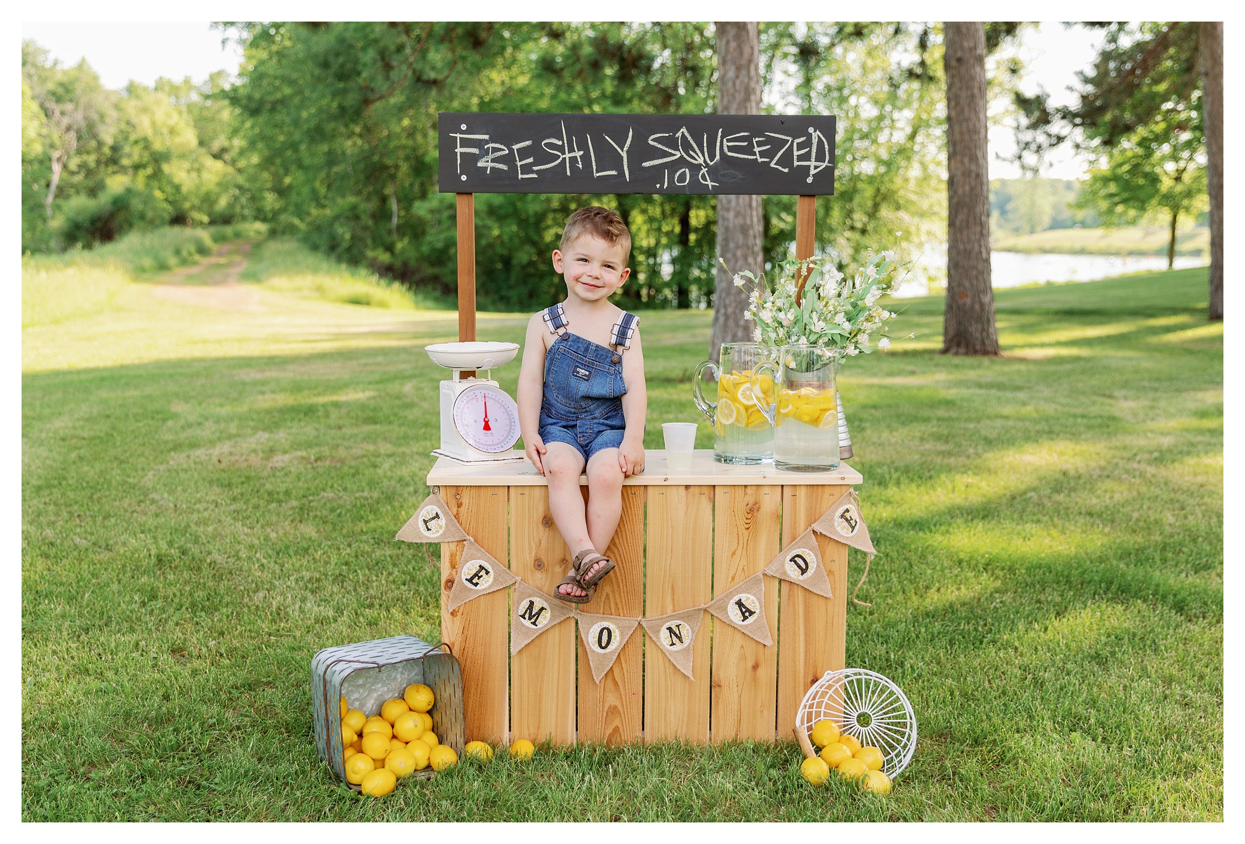 Toddler boy poses on lemonade stand during his Wausua, WI mini session at Sunnyvale Park