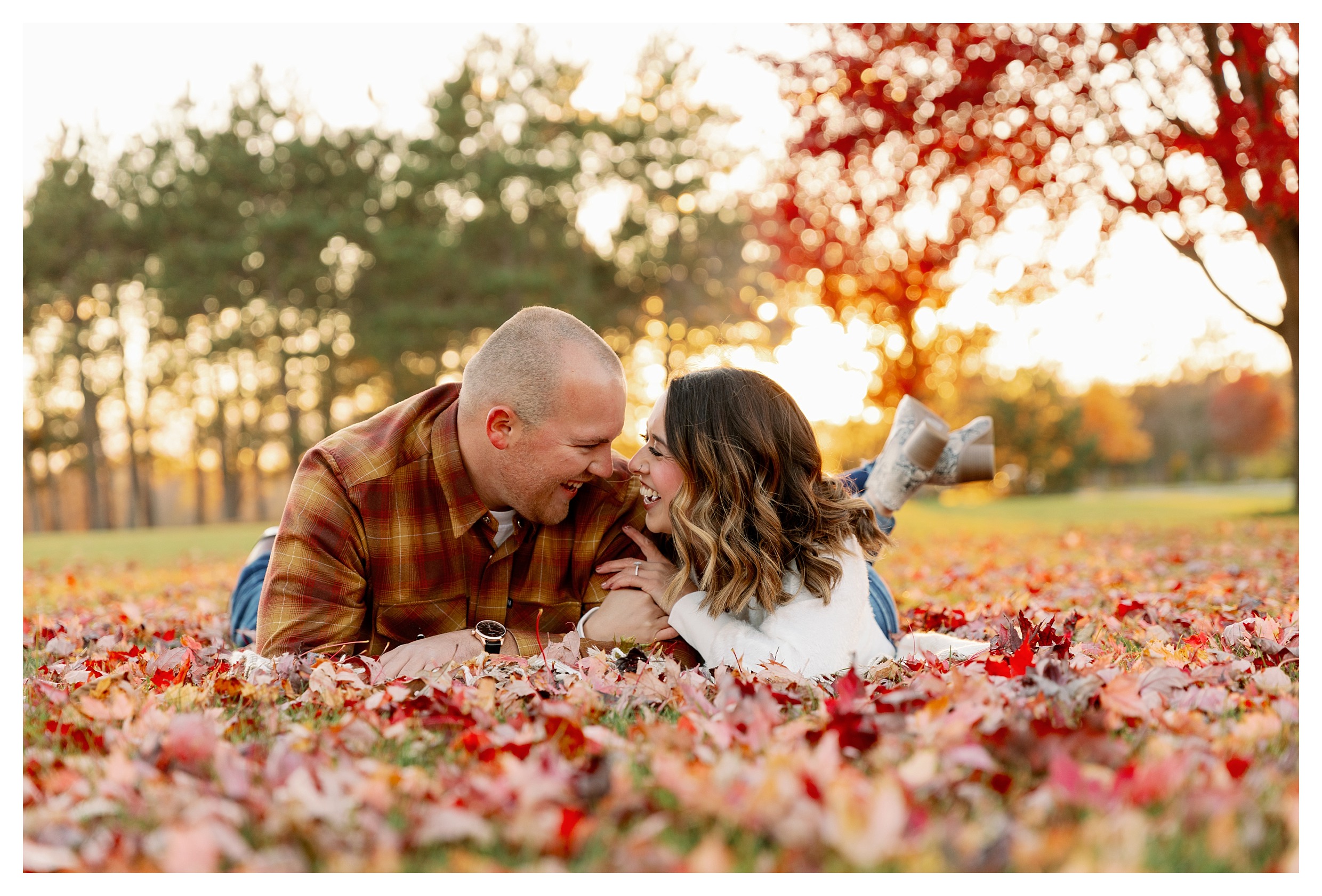 ouple taking fall engagement photos at park 